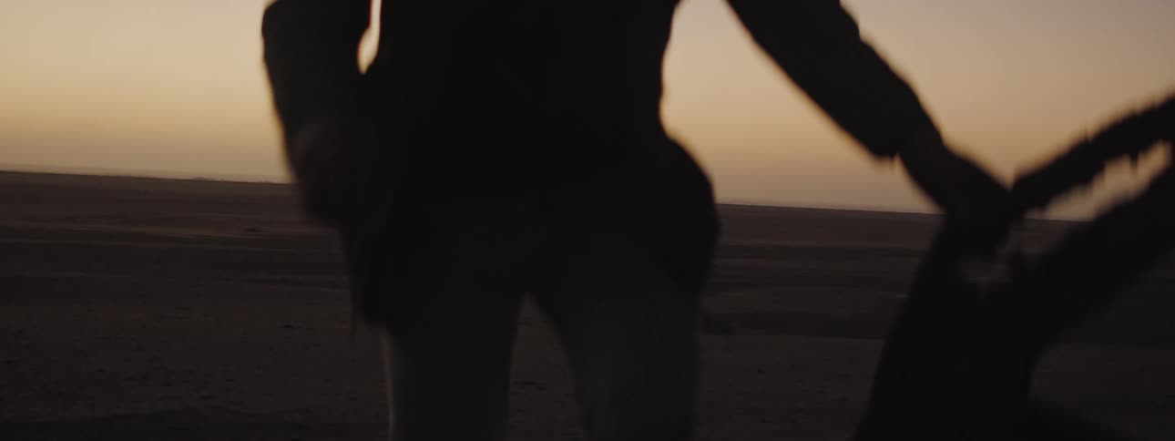 Silhouette of a man climbing on the ruins of a shipwreck in the desert at evening
