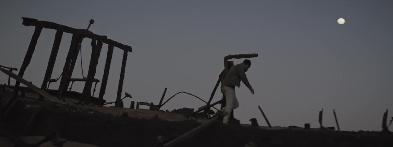Man walks through the ruins of a shipwreck