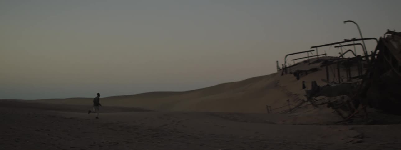 A man running on the beach to a shipwreck