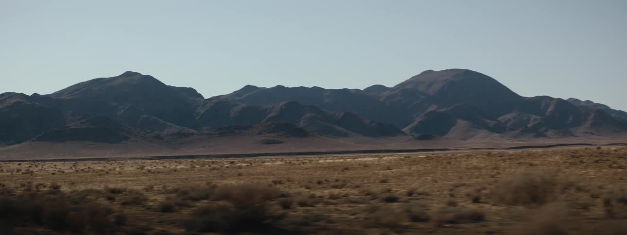 Wide shot of a desert mountain range from moving vehicle