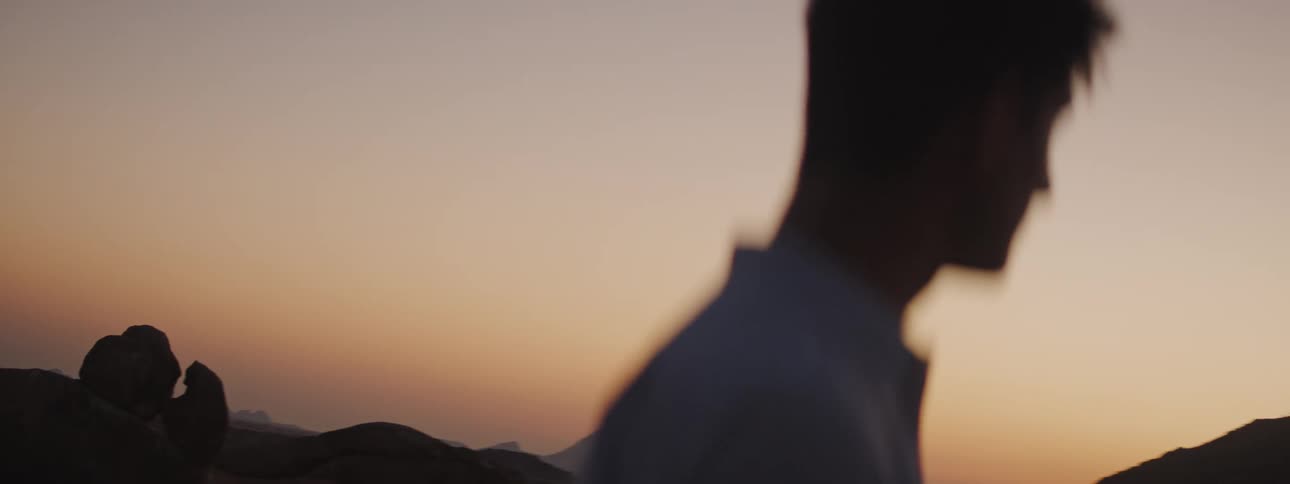 Silhouette of a man standing and looking at rock formations in the desert