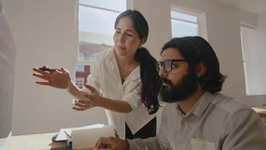 Woman supervises work of a designer in front of a computer in the office