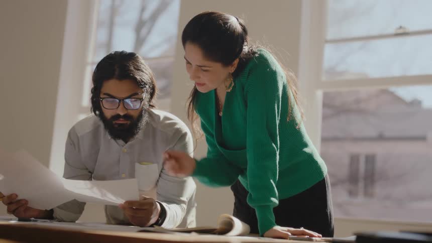 Colleagues go through binders and discuss paperwork in a conference room