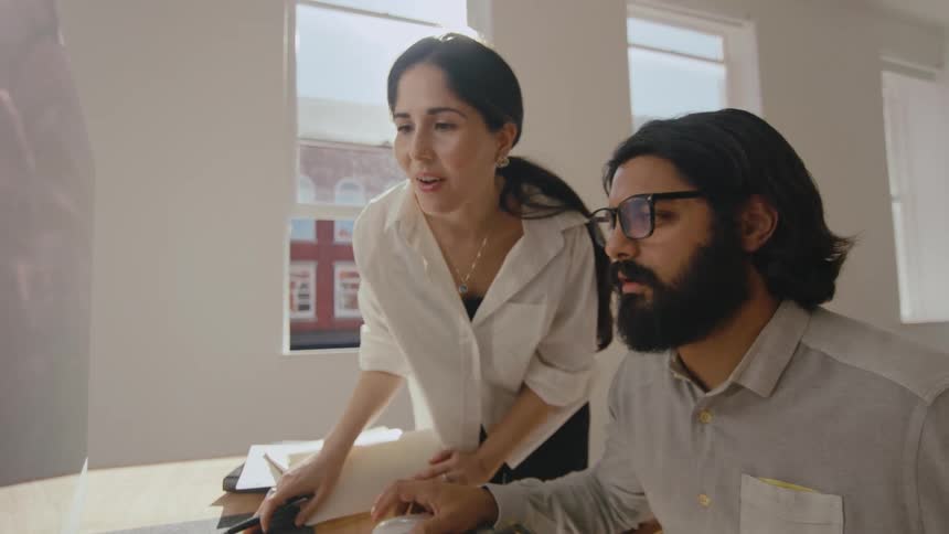 Coworkers look at a computer in the office