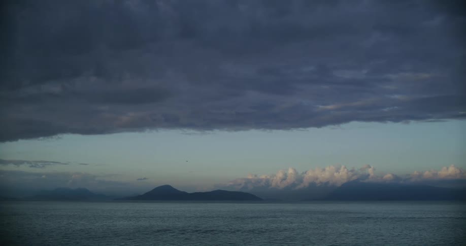 Heavy gray storm clouds hanging over flowing ocean water surface
