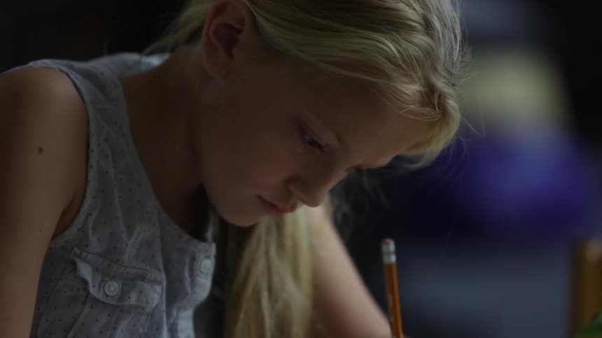 A girl is writing with a pencil