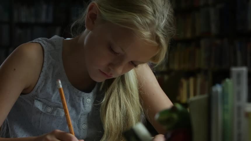 A girl is writing with a pencil