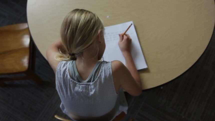 A girl is writing at a table