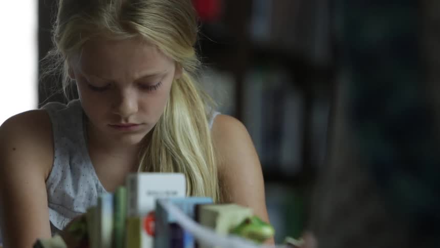 Girl rips out a piece of notebook paper while looking frustrated and hands it to another person