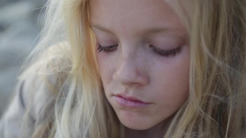 A blond girl adjusts her hair and looks around