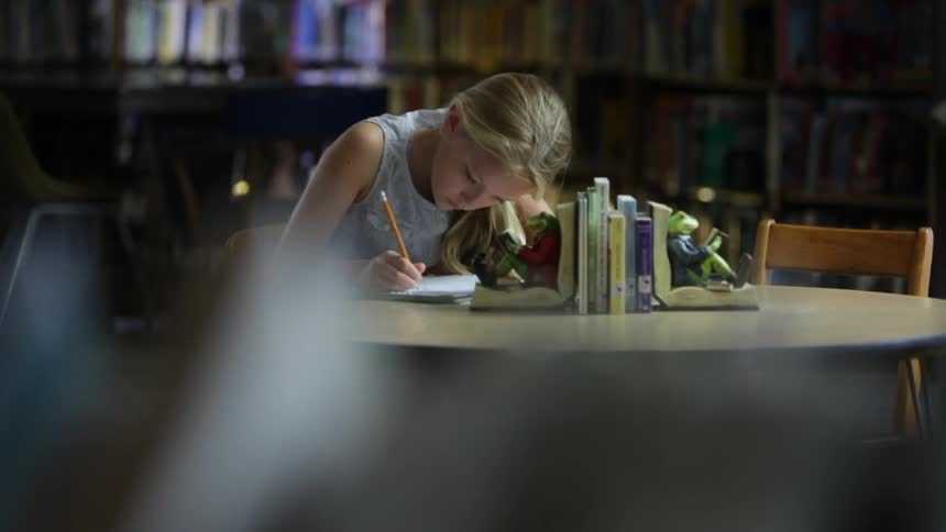 A girl is writing with a pencil