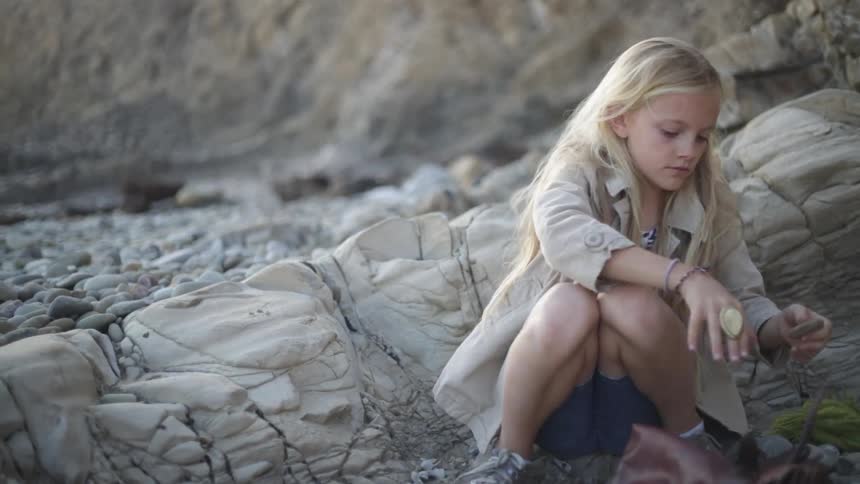 A girl picks up a rock and puts it in her bag