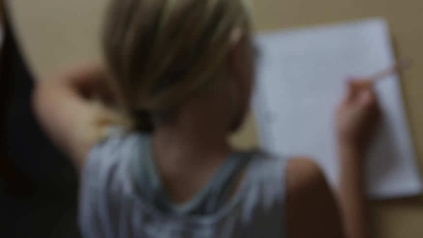 A girl is writing in a book at a table