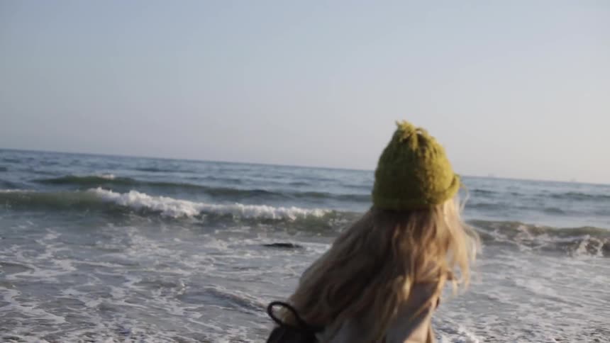 A girl throws a rock into the ocean