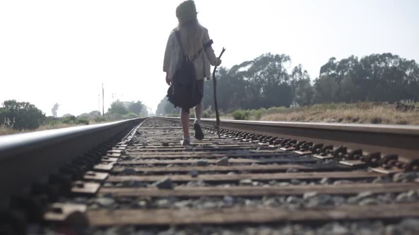 A girl is walking down railroad tracks