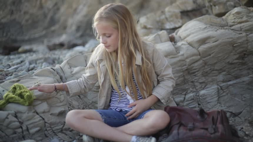 A girl sits down and chooses rocks to put in her bag