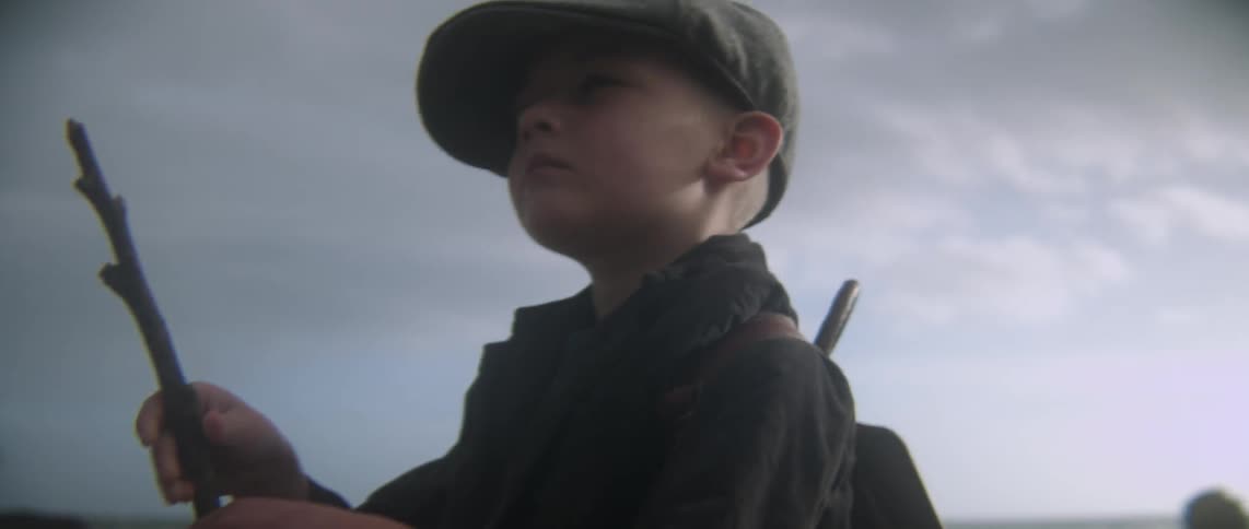 A boy is holding a stick on the beach