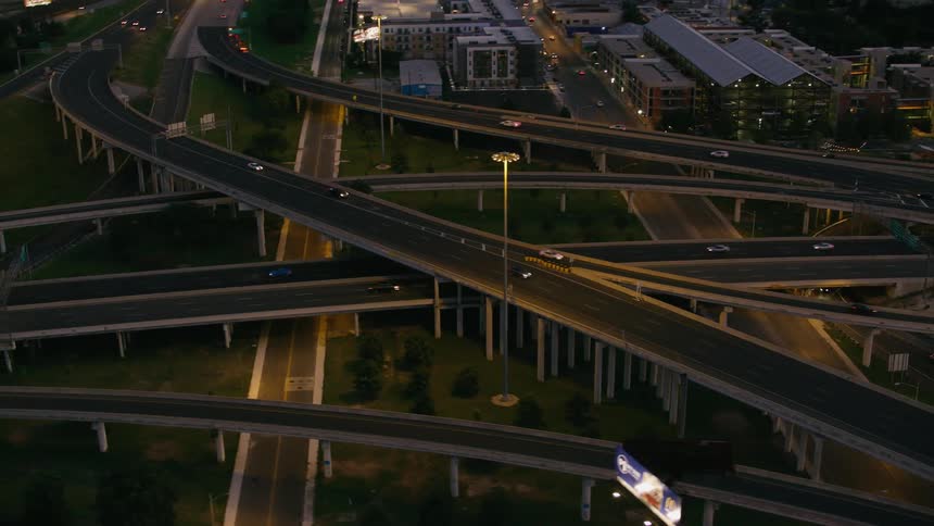 Cars traveling on a lamp lit highway system with on and off ramps and overpasses