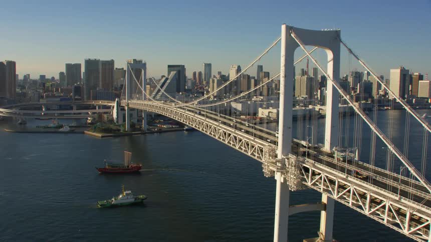 Traffic on the tokyo city rainbow bridge and boats traveling in the water
