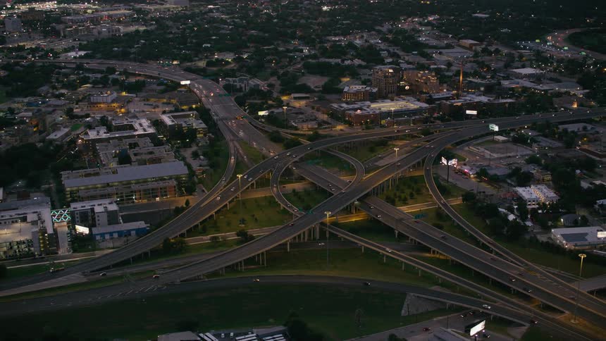 Heavy traffic passes over multiple highway overpasses that run through a city