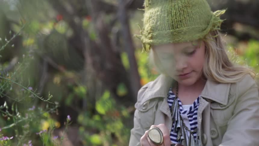 A girl adjusts her hat and removes a pen from a bag