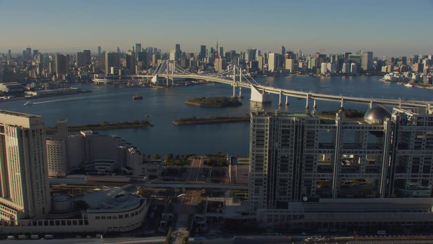 A long bridge spanning a large waterway in a metropolis during the day