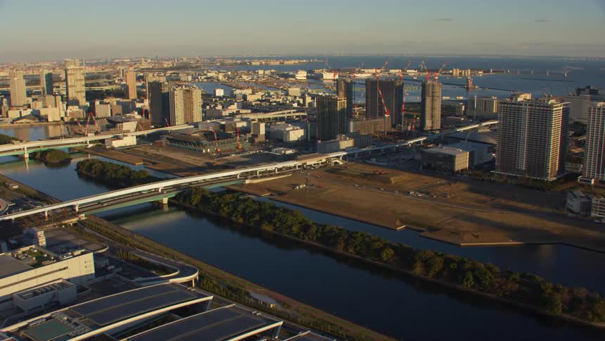 An aerial view of cars driving through a city with a river running through it surrounded by apartment buildings and high rise office buildings