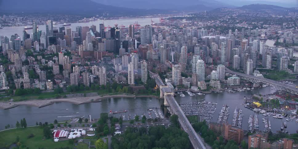 An aerial view of a city skyline on the river with boats docked