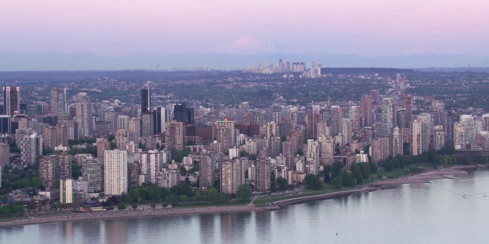 Aerial view of big city skyline with high rise buildings next to river at dusk