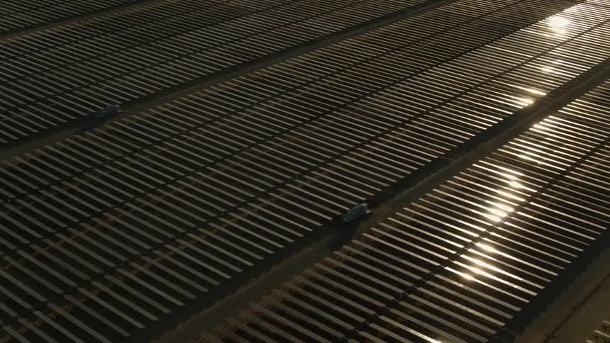 The sun shines brightly on solar panels on a solar farm