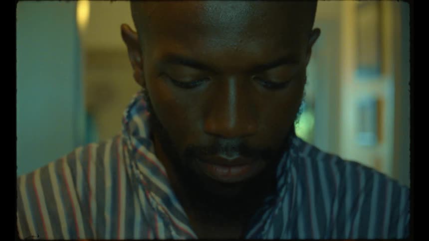 A close up of a mans face as he stands at home and looks down as he is probably doing dishes