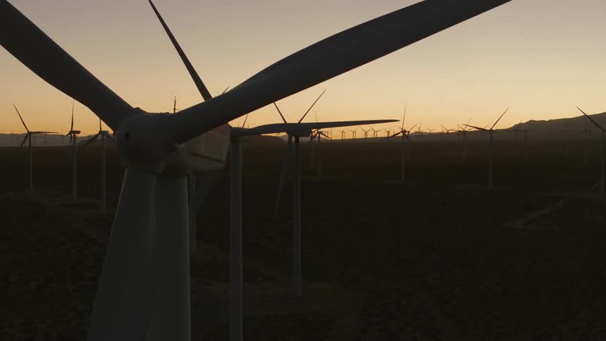 Silhouettes of wind turbines in a field on a wind farm