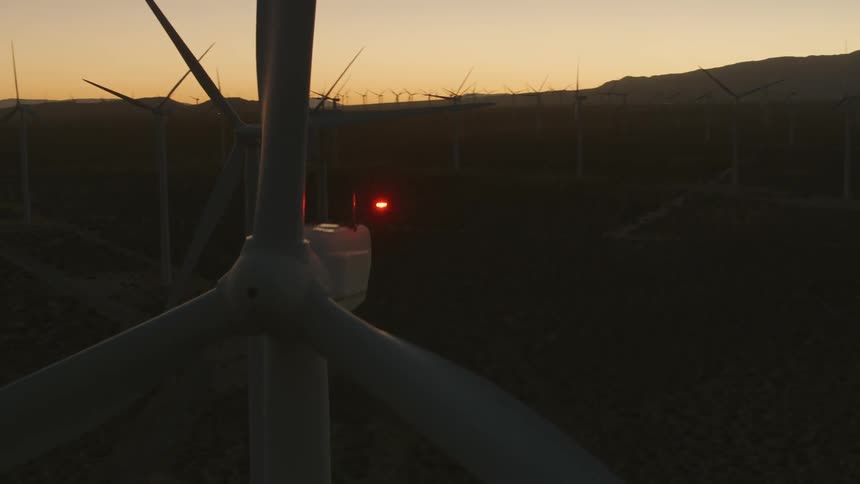 Shut down wind turbines fill a field near rolling hills