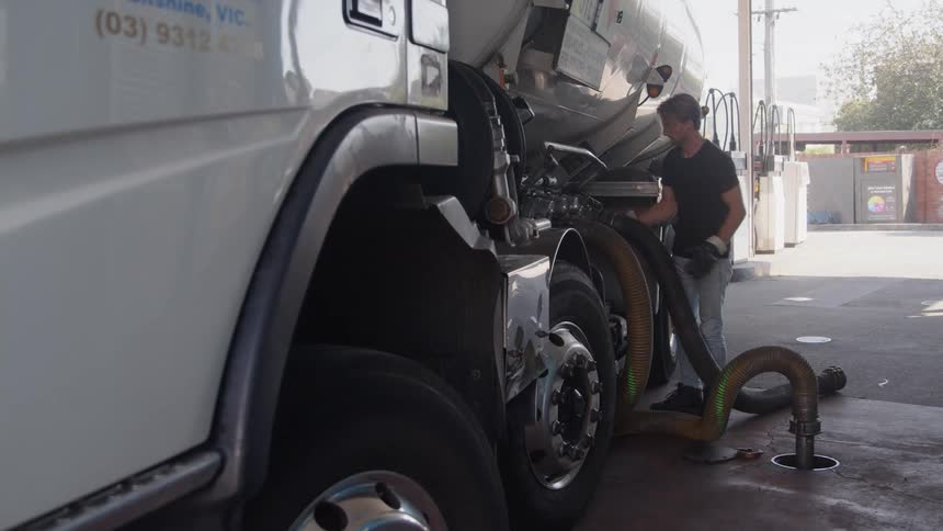 A man attaches the hose to his gas truck