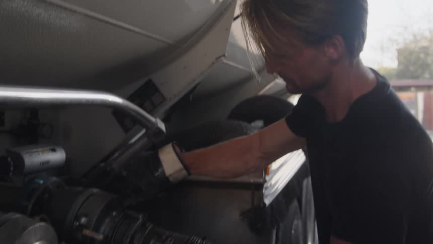 Man wearing gloves attaches hose to tanker truck