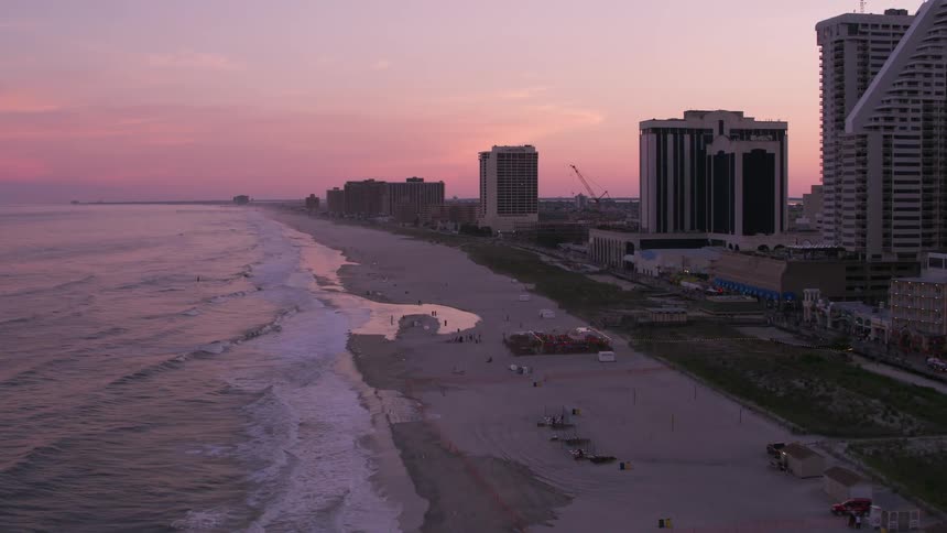 Aerial view of people on the beach next to ocean at dusk