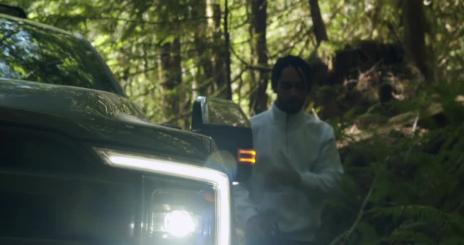 A man is getting out of a vehicle near the forest