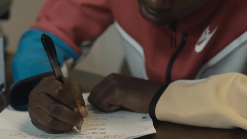 Man sits at table answering questions on paper