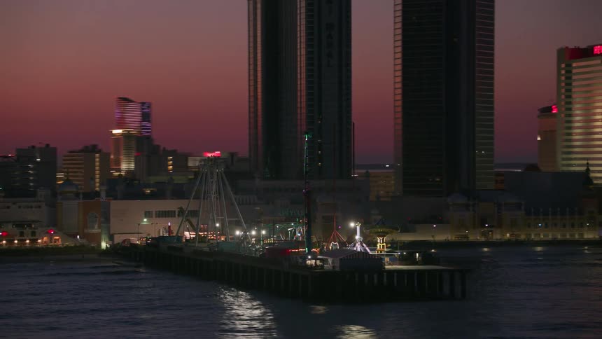 An amusement park on a boardwalk in front of hotels on the shore