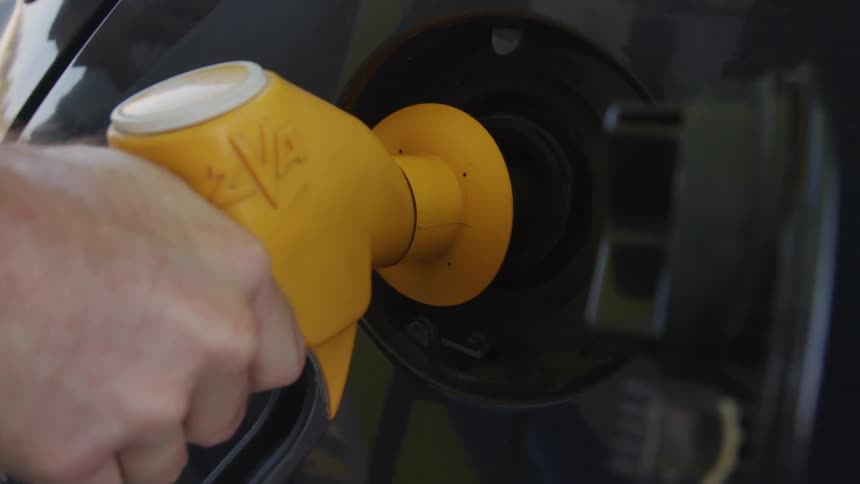 A person is putting gas in their car during the day