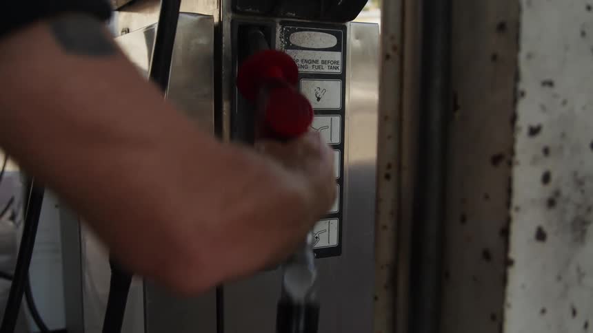 A man lifts the gas pump at the station
