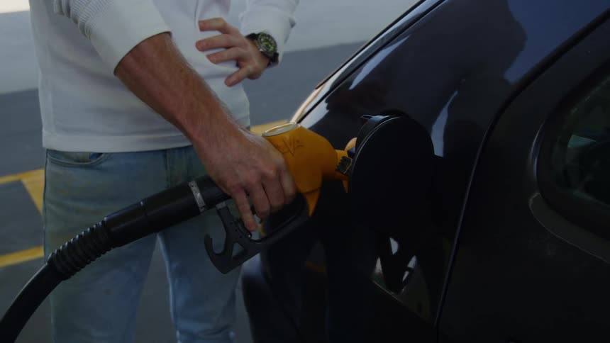 A man frowns will filling his gas tank