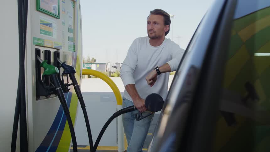 A man is putting gas in his car during spring