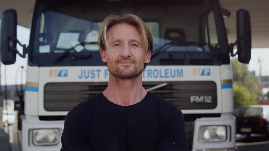 A man is standing outside of his parked vehicle