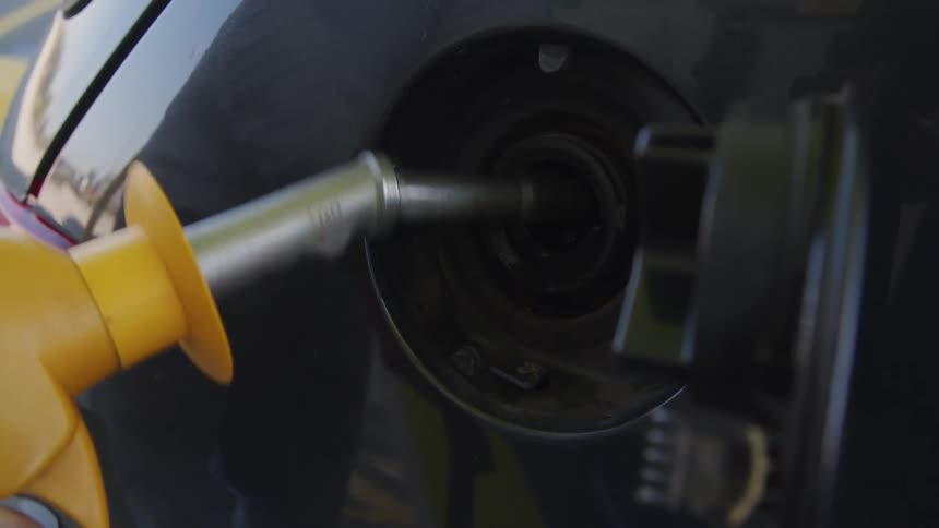 A man shakes off the nozzle after getting gas at a station