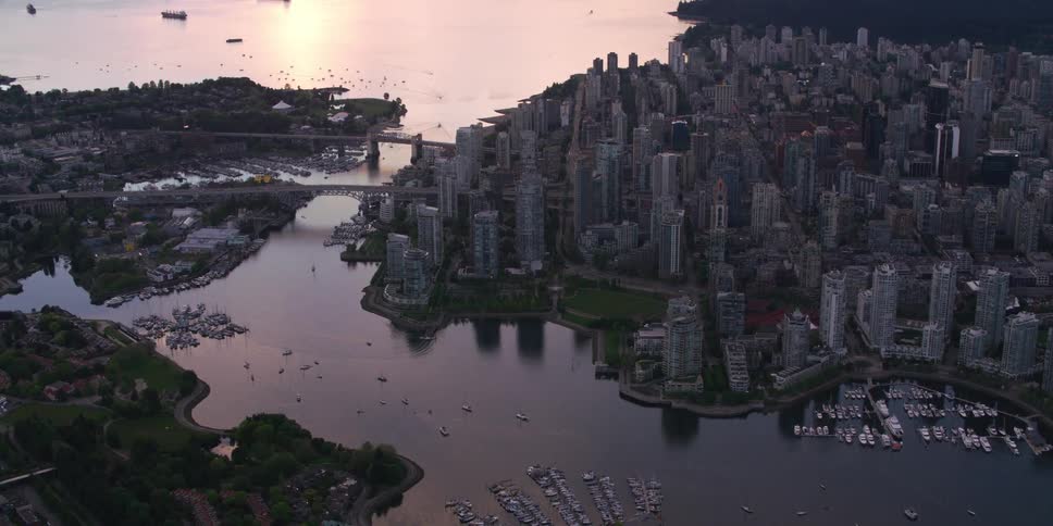 Boats sit near a bridge that leads to a coastal city