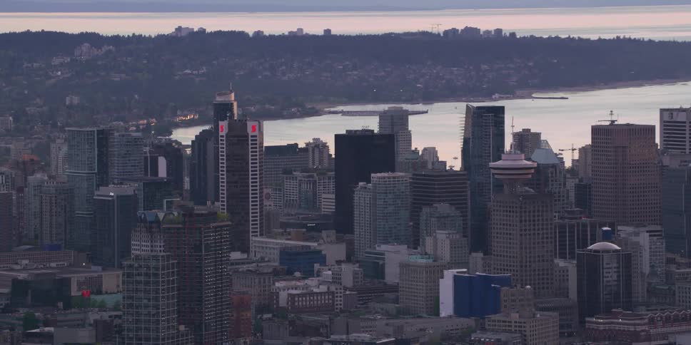 An aerial view of high rise office buildings in a city with boats in the water behind them