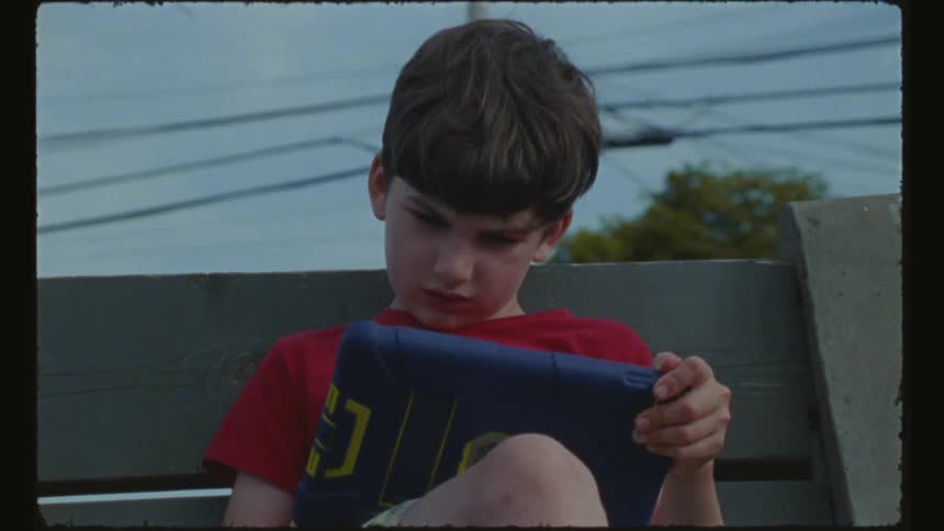 A child is using a tablet on the bench