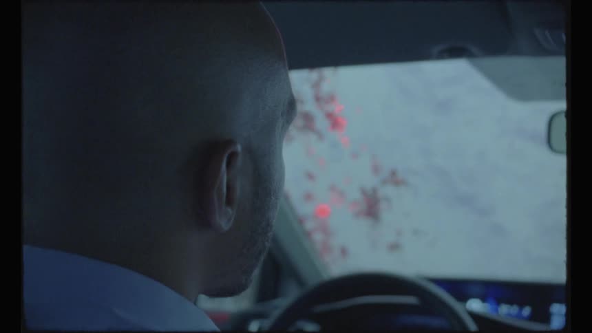 Man sitting on the driver seat of a car going through a car wash caught on vintage film