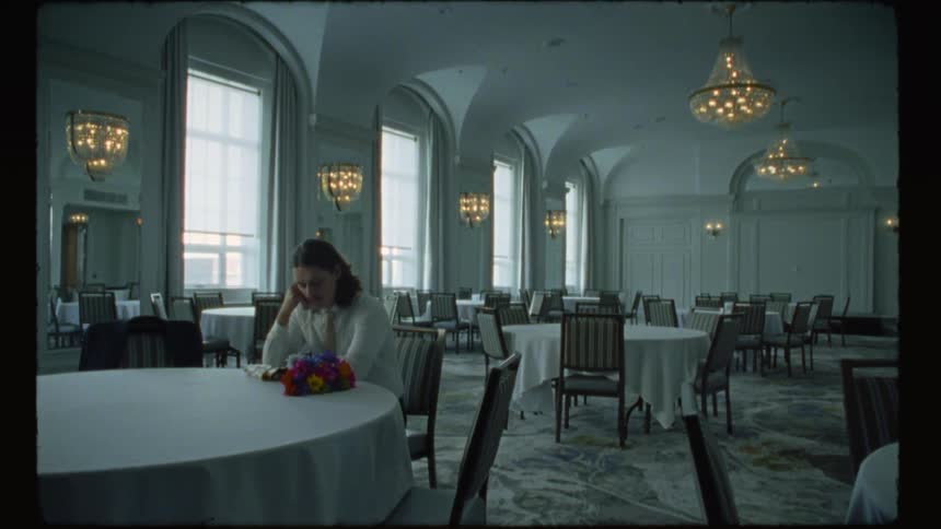 A woman is sitting at a table in an empty room
